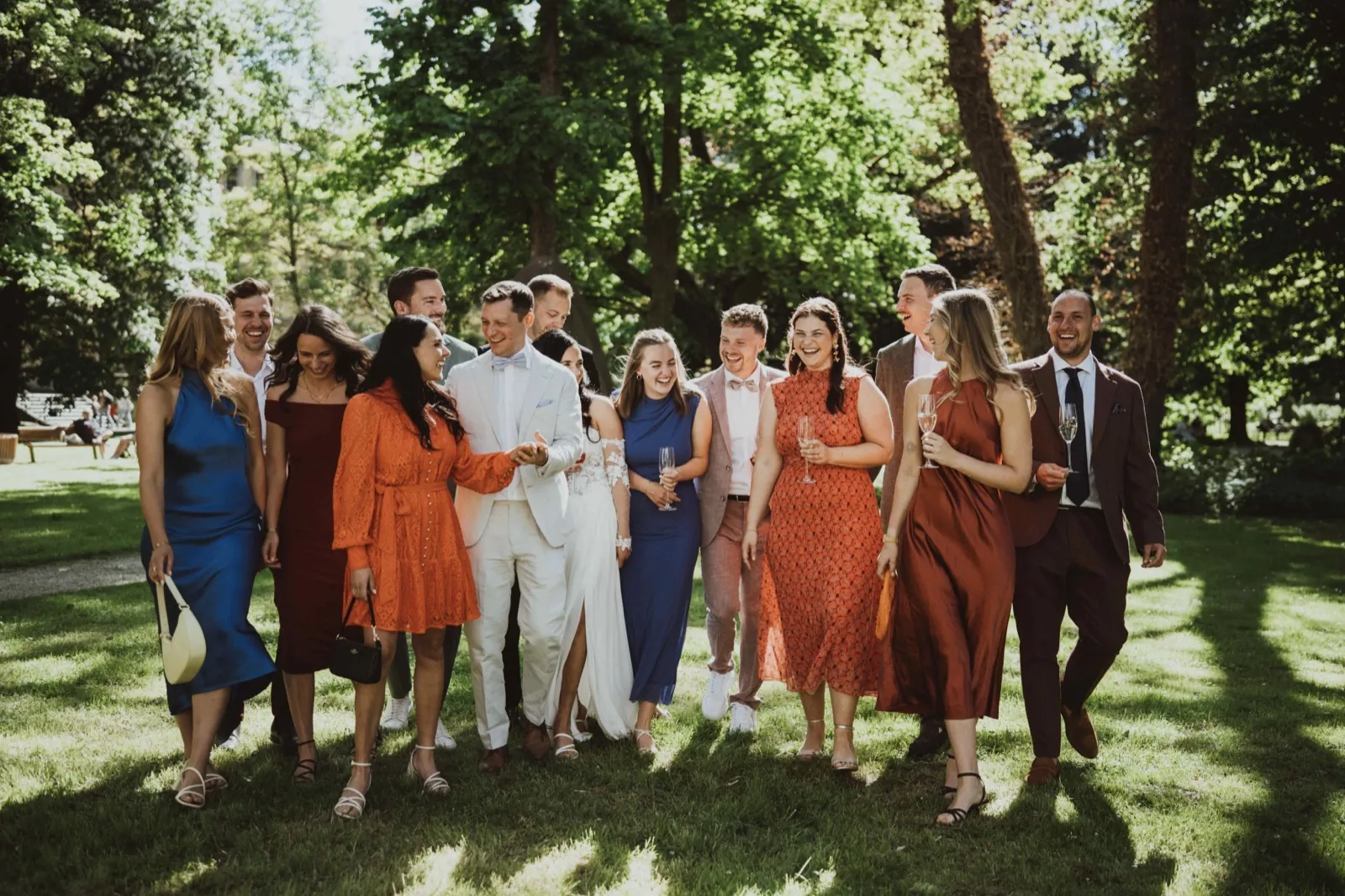 Caro & Dominik – Eine Hochzeitsgesellschaft läuft lachend über eine Wiese im Park