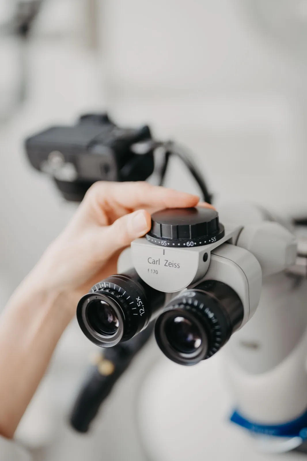 May – Eine Hand stellt ein Carl Zeiss Mikroskop in einer medizinischen oder wissenschaftlichen Umgebung ein